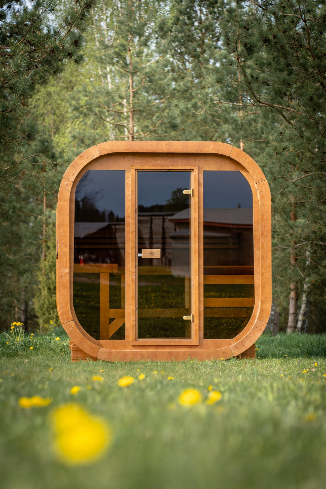 PlusLife Max Traditional Sauna 2.0 outdoor cabin: rounded square timber frame, full glass front with a glass door, timber benches visible inside