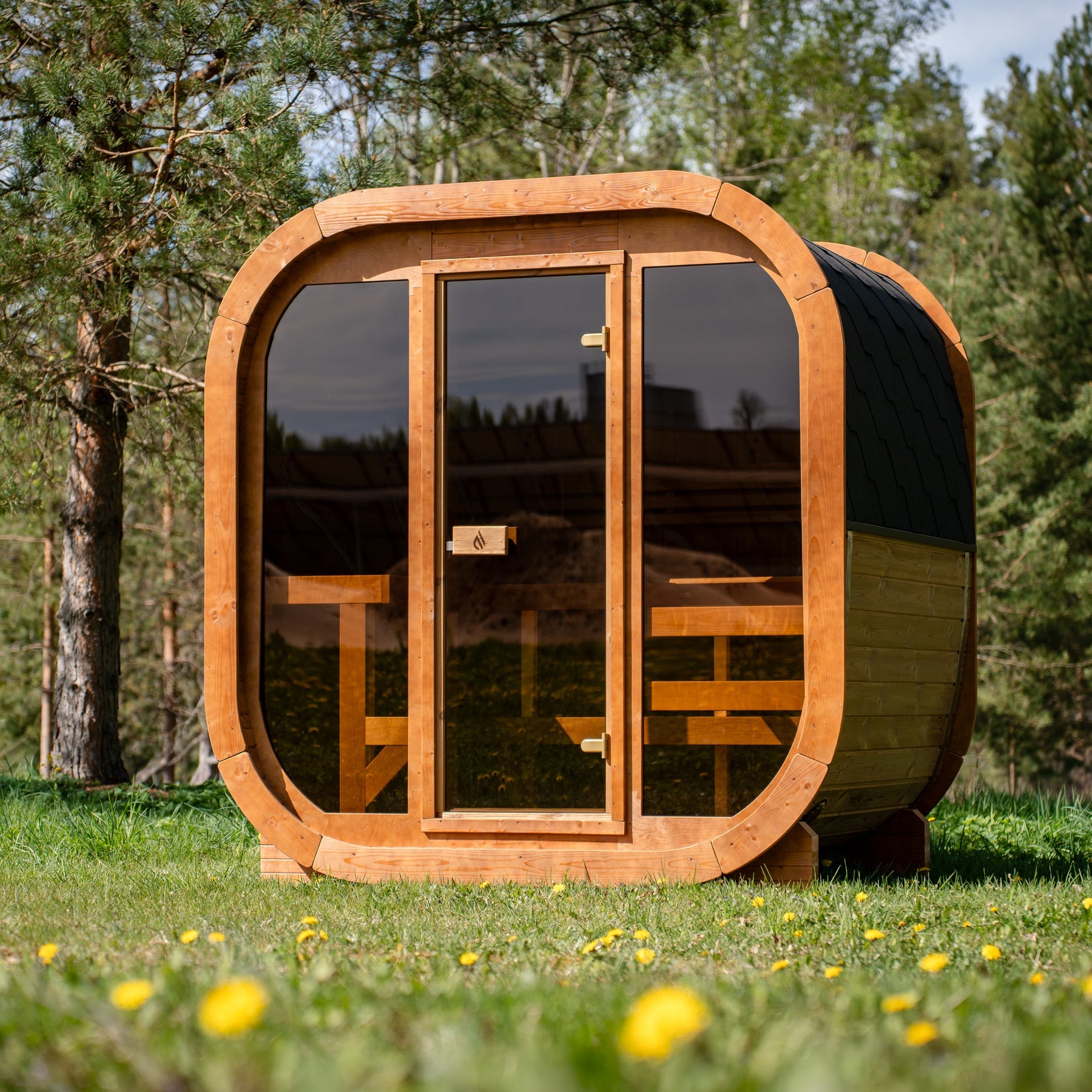 PlusLife Max Traditional Sauna 2.0, a rounded-square outdoor cabin with a full tinted-glass front and black shingle roof