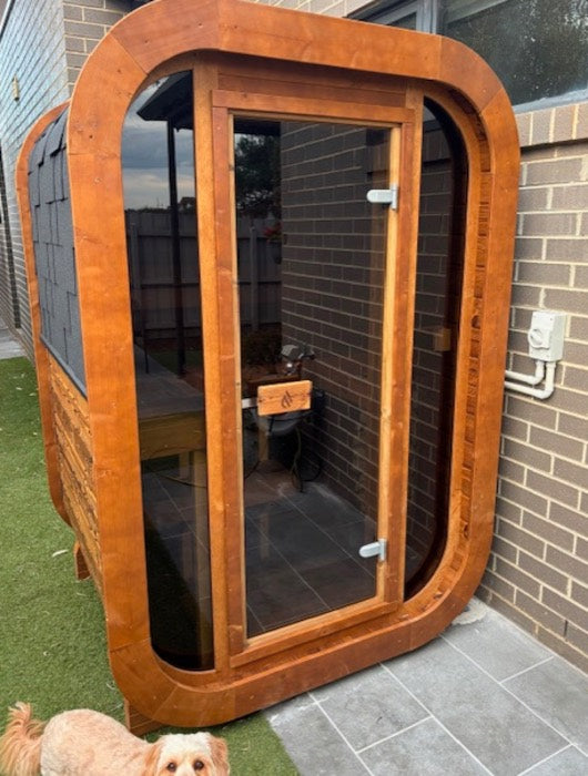 Compact sauna against a brick wall at the side of a house