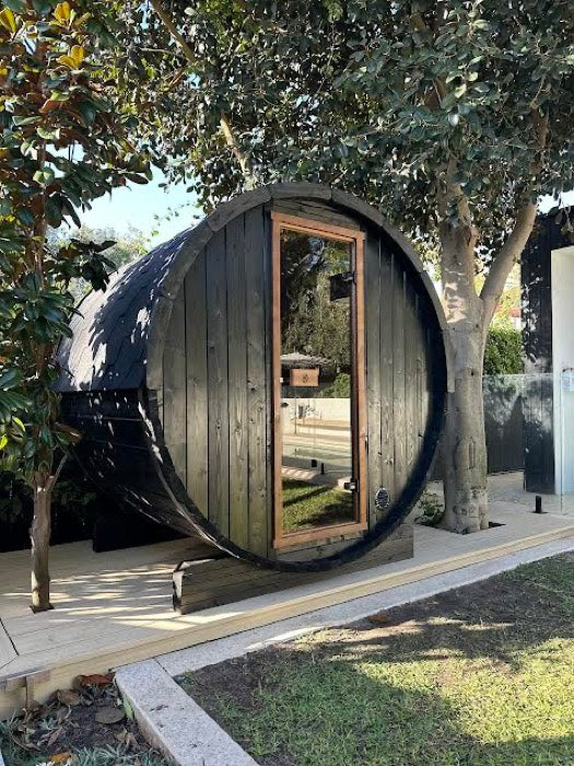 Black barrel sauna in a garden